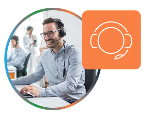A smiling man wearing glasses and a headset is seated at a desk