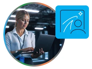 A woman wearing a white blouse is working on a laptop in a dimly lit, industrial-style room