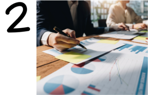 The number 2 is on the left. On the right, people sit at a table in a bright office, reviewing business charts and graphs related to Sales and Operations Planning, taking notes with pens and sticky notes amid paperwork.